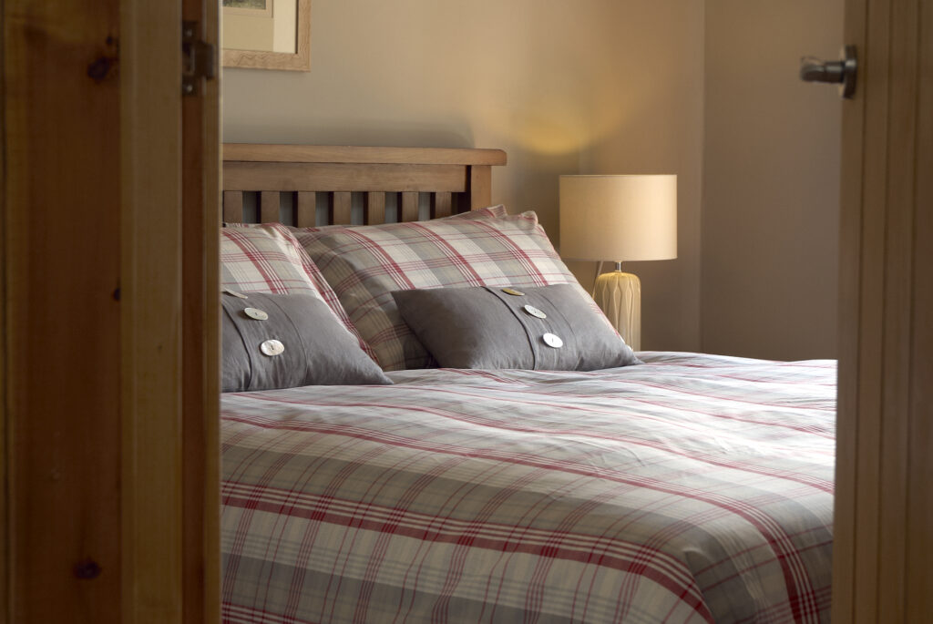Green bedroom with king-size bed and soft furnishings in the converted barn